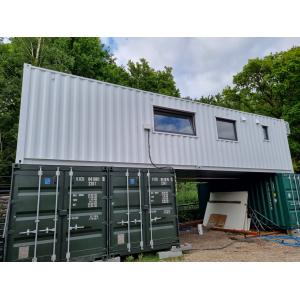 Container home construction process showing white-finished upper level with modern windows, mounted on green shipping containers, demonstrating KC Cabins' 8-12 week transformation timeline