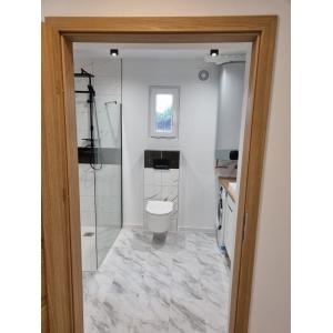 Luxury container home bathroom featuring marble-effect tiles, walk-in shower, integrated laundry, and modern sanitaryware by KC Cabins Solutions