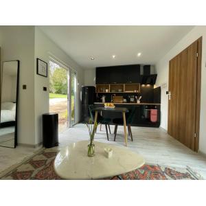 Modern open-plan container conversion interior featuring contemporary kitchen with black units, wooden dining table, engineered flooring, and natural light from large windows - KC Cabins luxury modular building