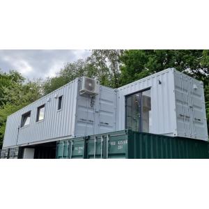 Modern luxury shipping container conversion featuring white upper level with multiple windows mounted on green storage containers, demonstrating KC Cabins' innovative Z-design modular building solution