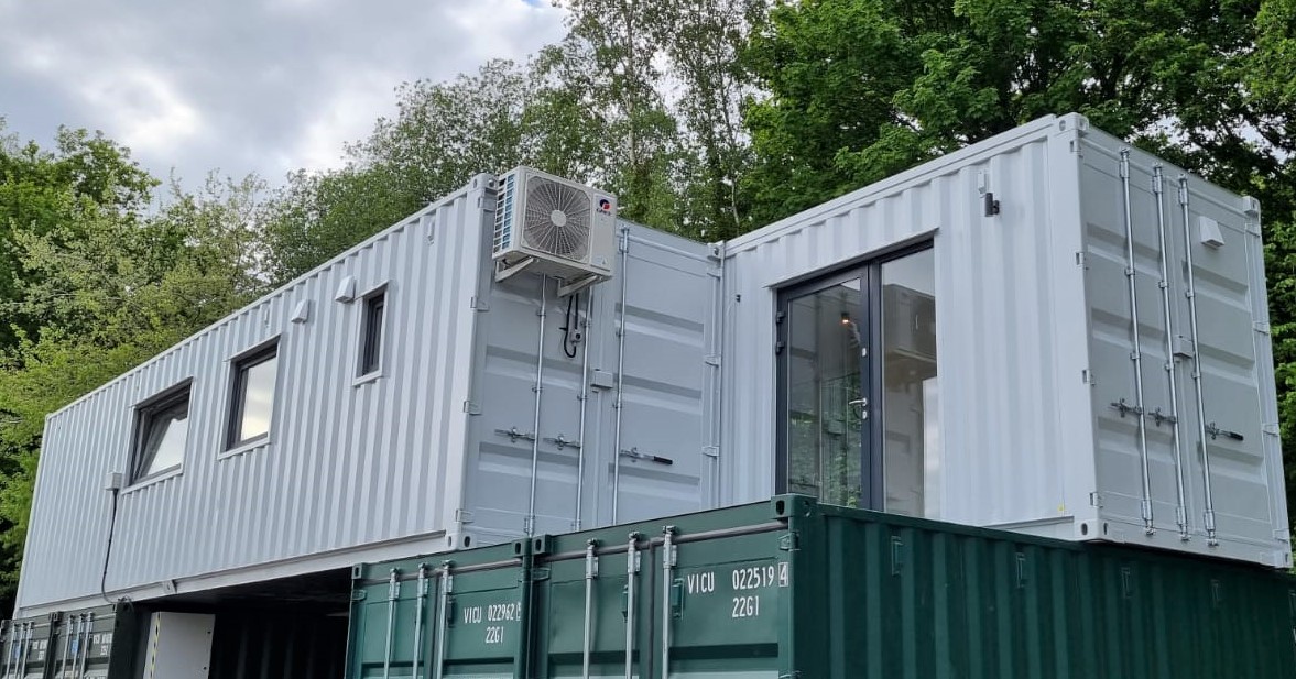 Large ISO frame modular office building with dark grey cladding and full-height glazing - multi-module permanent commercial office