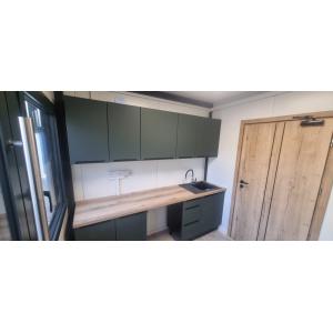 Modern commercial kitchen with sage green cabinets and wooden countertops