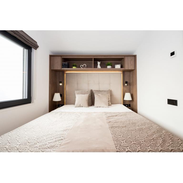 Luxury mobile home master bedroom with built-in storage, LED lighting, and designer bedding