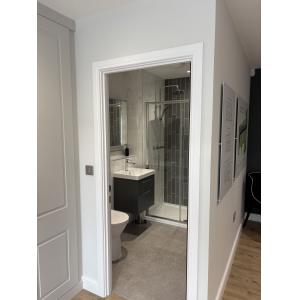 Contemporary marketing suite bathroom with grey metro tiles, rainfall shower, wall-hung vanity unit and marble-effect panels by KC Modular Buildings