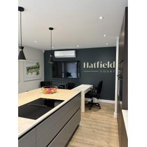 Branded Hatfield Court marketing suite interior with feature wall signage, consultation desk, presentation screen, kitchen island and air conditioning by KC Modular Buildings