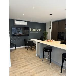 Open-plan Hatfield Court marketing suite with branded feature wall, breakfast bar, consultation seating, presentation screen and climate control by KC Modular Buildings