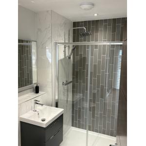 Marketing suite specification bathroom with grey metro tiles, marble-effect panels, rainfall shower enclosure, wall-hung vanity and contemporary chrome fixtures by KC Modular Buildings