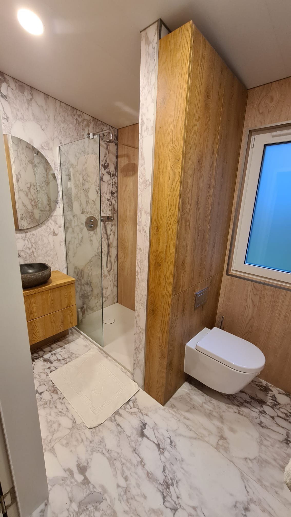Luxury modular lodge bathroom with marble-effect wall finish, timber panelling, walk-in shower and wall-hung WC