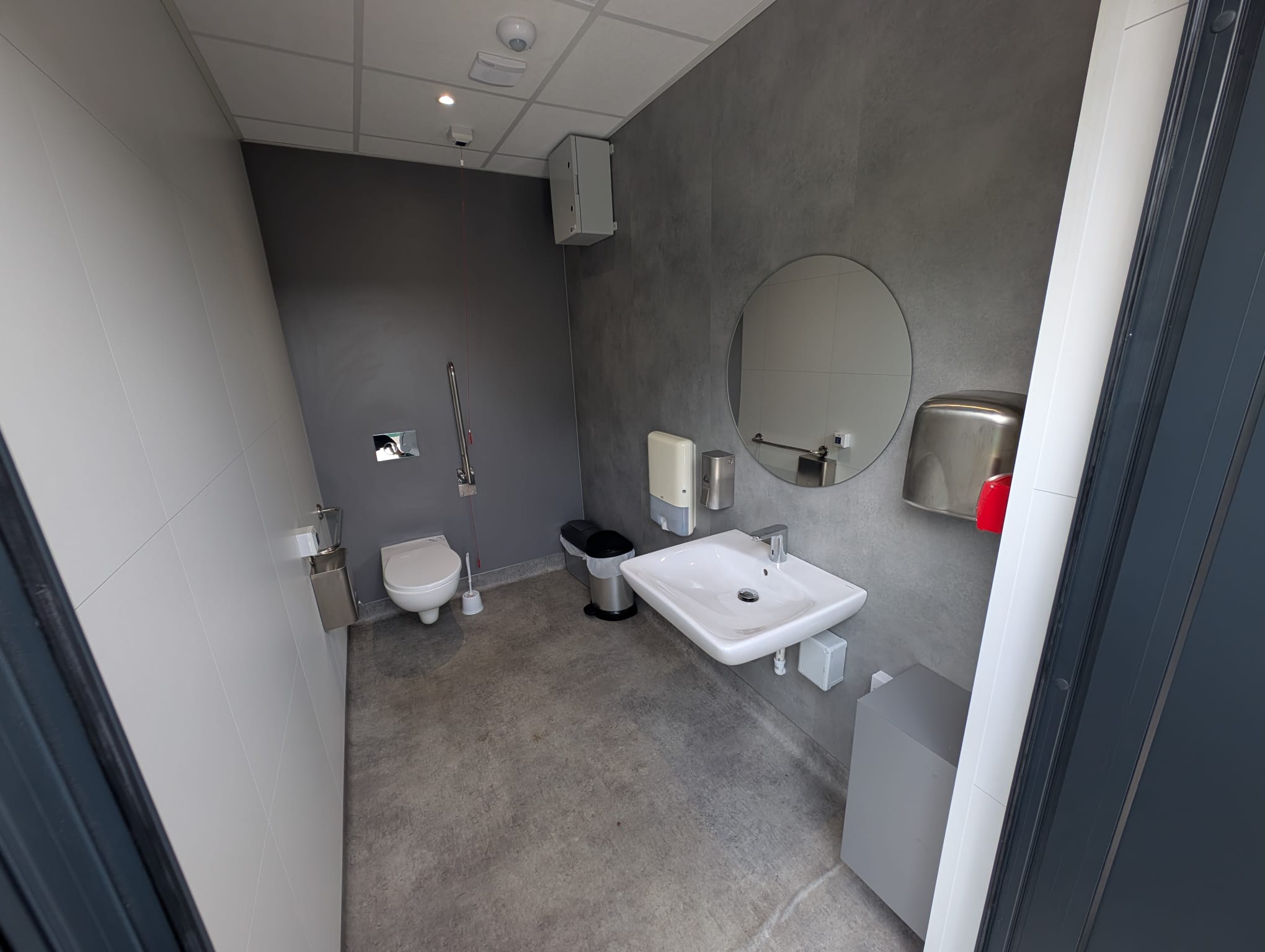 Accessible WC inside the modular welfare unit at St George’s Park, with wash basin, mirror and hand-drying facilities.