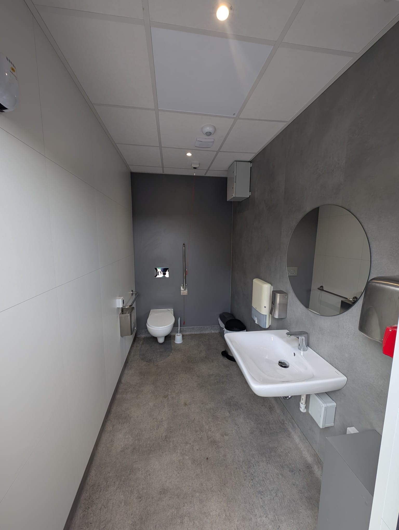 Accessible modular welfare facility with WC, wash basin, mirror, bins and hygiene fittings.