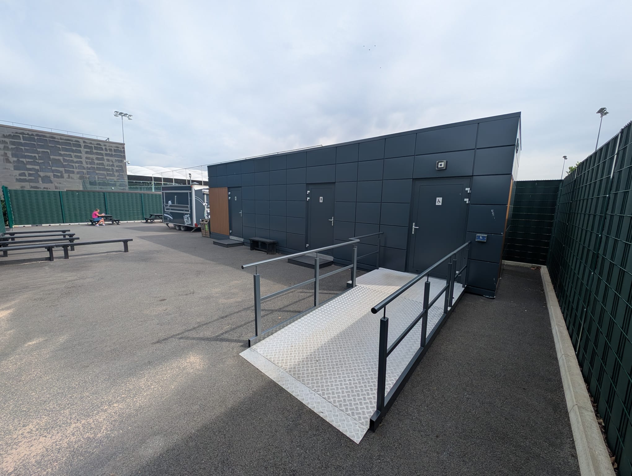 Dark-clad modular welfare unit at St George’s Park with accessible ramp, handrails and external access doors