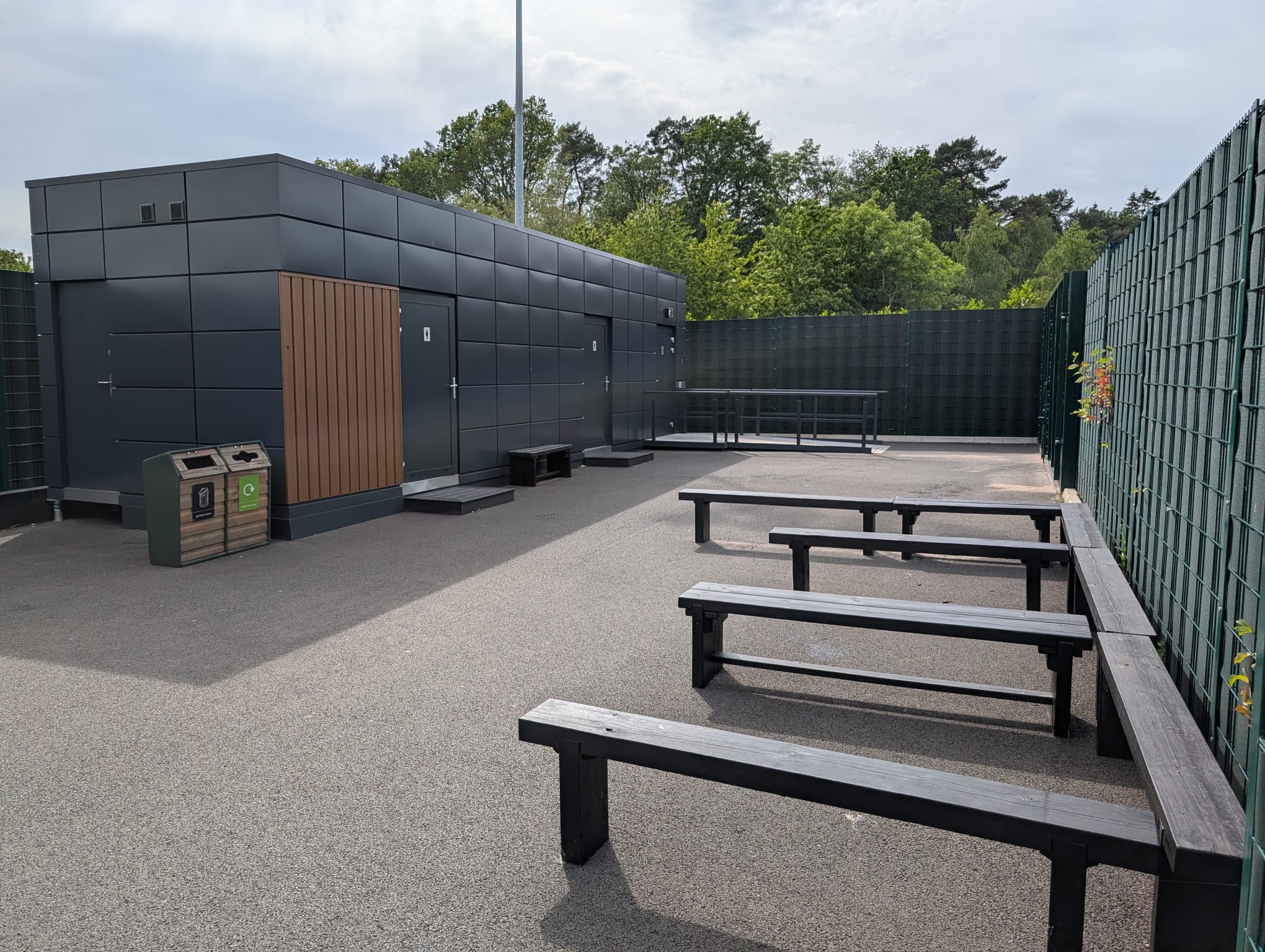 Dark-clad modular welfare unit at St George’s Park with accessible ramp, handrails and external access doors.