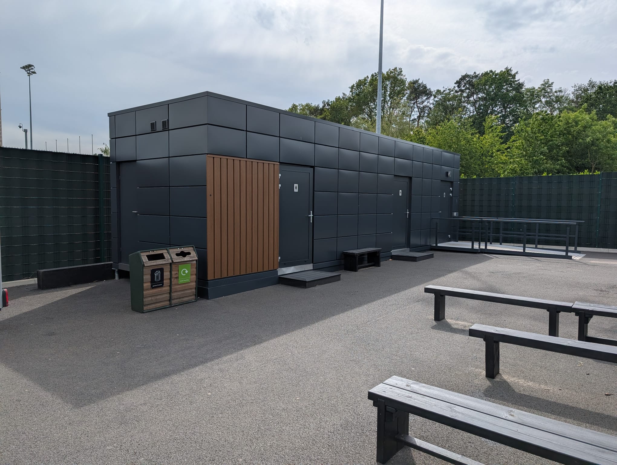 Exterior view of the dark-clad modular welfare unit at St George’s Park with external doors and accessible ramp.